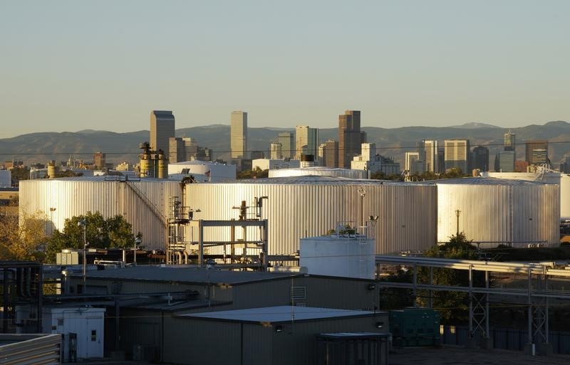 © Reuters. Oil storage tanks are seen at sunrise with the Rocky Mountains and the Denver downtown skyline in the background