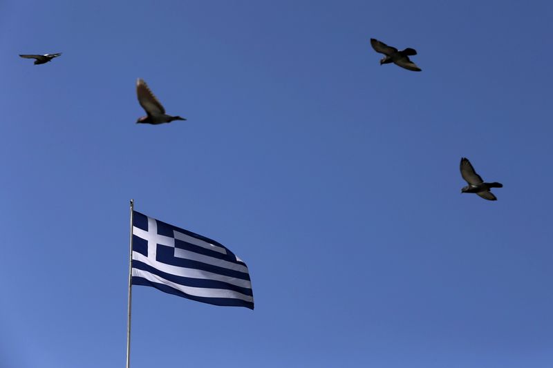 © Reuters. Pigeons fly over a fluttering Greek national flag in Athens