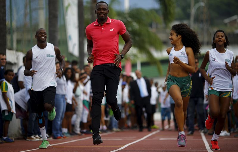 © Reuters. Usain Bolt corre ao lado de jovens da Vila Olímpica da Mangueira