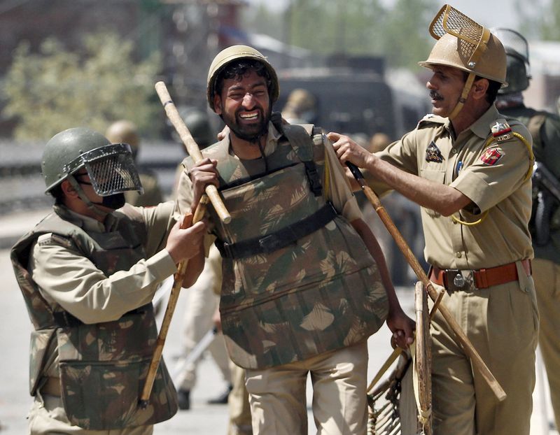 © Reuters. An Indian policeman is being helped by colleagues after he was injured in a clash with Kashmiri protesters during a daylong protest strike in Narbal, north of Srinagar