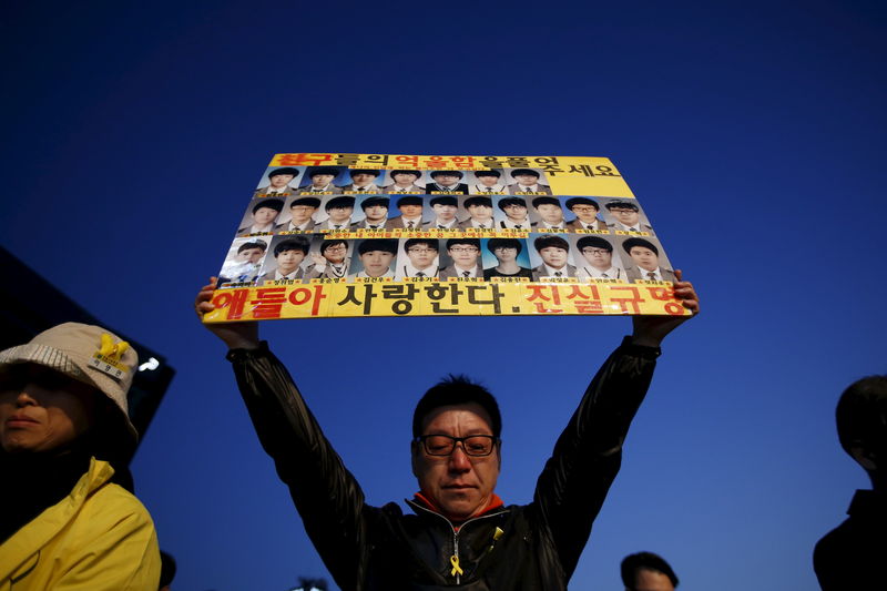 © Reuters. A mourner holds up banner depicting students who died in sunken ferry Sewol during rally to commemorate first anniversary of the Sewol ferry disaster, in central Seoul