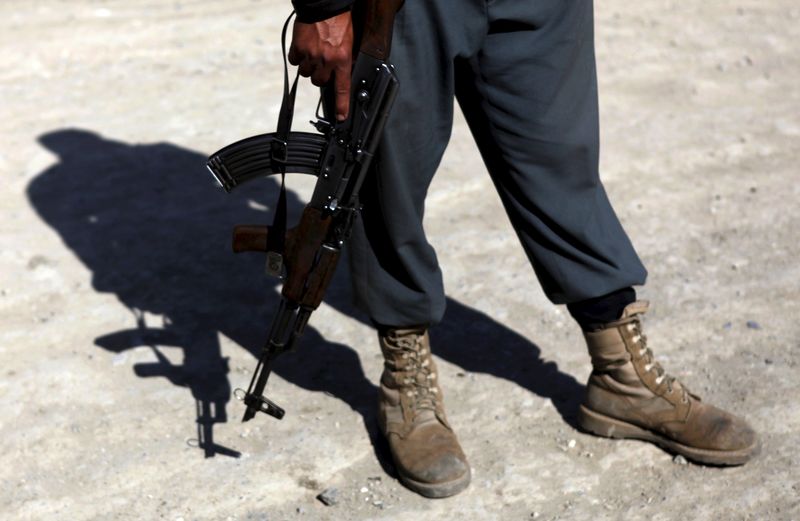 © Reuters. File picture shows an Afghan policeman with a weapon standing at the site of a suicide attack in Kabul