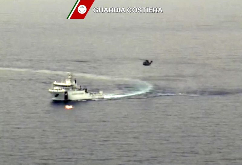 © Reuters. Imagen tomada de video. Nave de la guardia costera italiana y helicóptero durante las operaciones de búsqueda y rescate de barco que naufragó frente a la costa libia