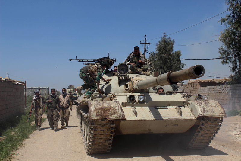 © Reuters. Kurdish peshmerga forces sit on top of a tank on the outskirts of Kirkuk