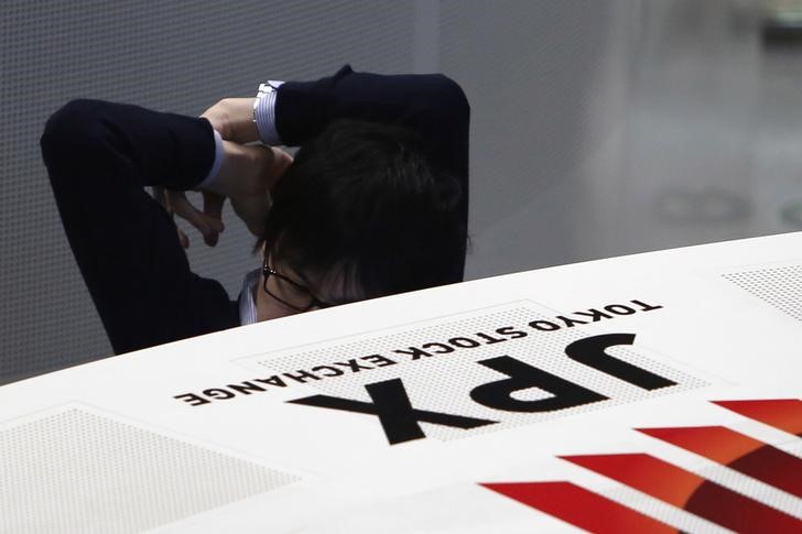 © Reuters. An employee of the Tokyo Stock Exchange stretches his body as he works at the bourse at TSE in Tokyo