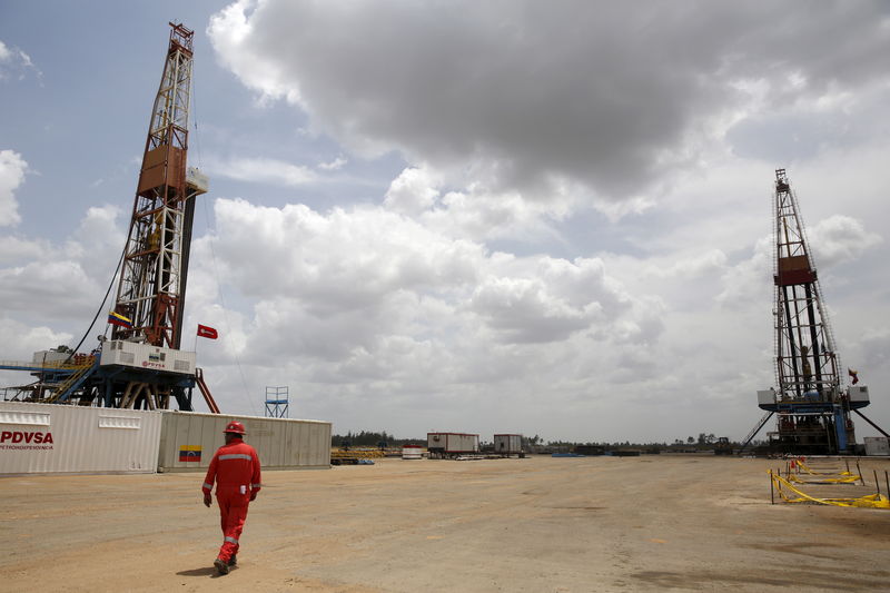 © Reuters. An oilfield worker walks next to drilling rigs at an oil well operated by Venezuela's state oil company PDVSA, in the oil rich Orinoco belt, near Morichal at the state of Monagas
