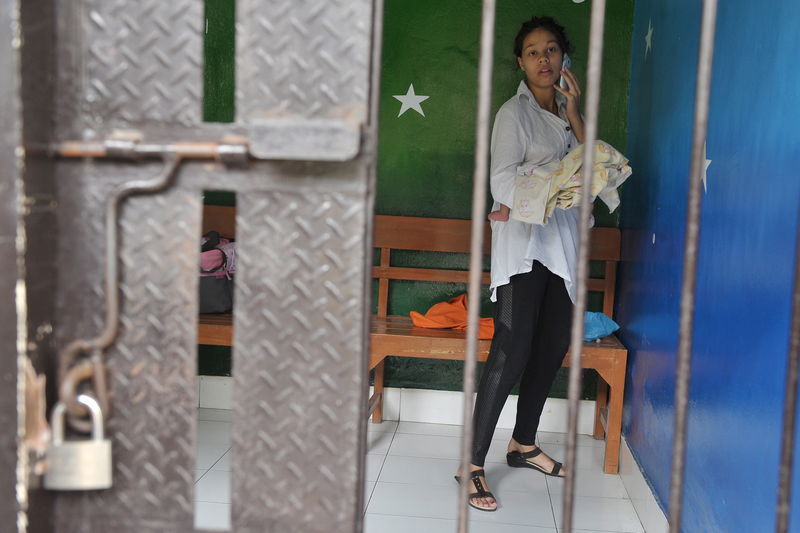 © Reuters. Mack uses a mobile phone inside a holding cell before her trial at Denpasar district court