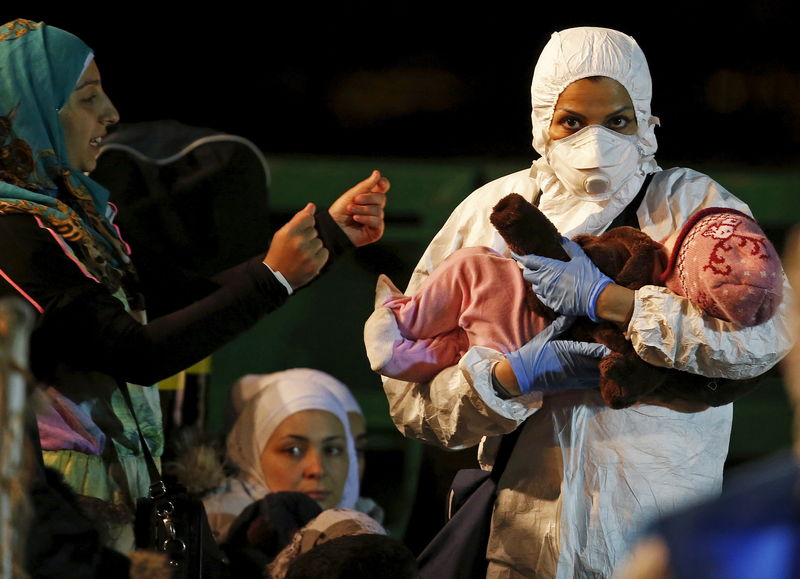 © Reuters. Criança carregada por funcionária de equipe de resgate na chegada de barco de imigrantes ao porto italiano de Pozzallo