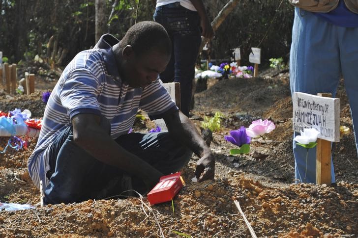 © Reuters. Sobrevivente do Ebola Stanley Juah chora no túmulo do filho, morto devido ao vírus, na Libéria