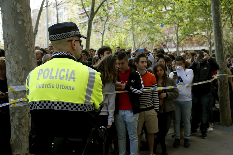 © Reuters. Policial e estudantes do lado de fora de escola em Barcelona onde houve ataque