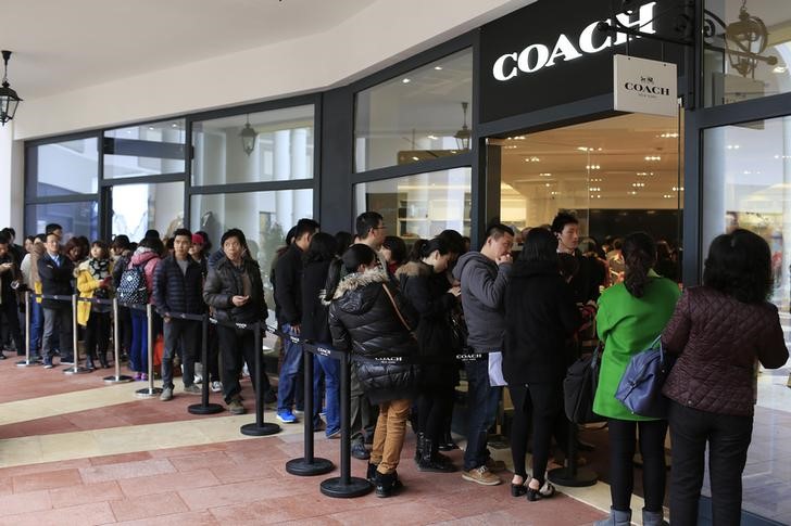 © Reuters. Consumers line up as they wait to go inside a Coach shop in Shanghai