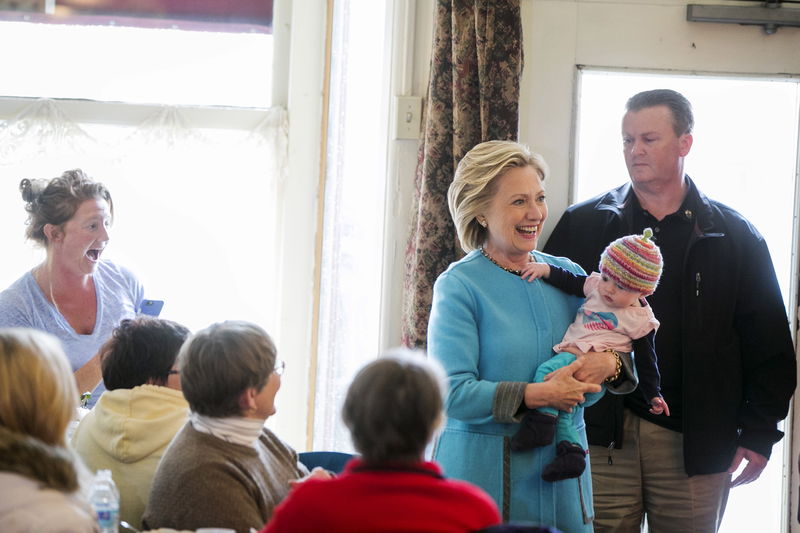 © Reuters. Hillary Clinton holds Molly Morse as Caron Morse takes a photograph inside Kristin's Bistro & Bakery while she campaigns for the 2016 Democratic presidential nomination in Keene