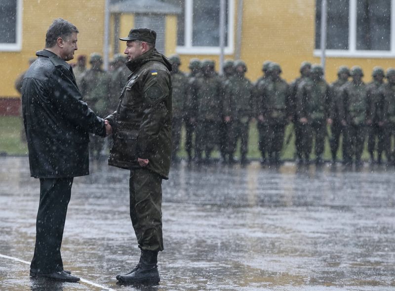 © Reuters. Ukraine's President Poroshenko shakes hands with a serviceman of Ukrainian National Guard during an opening ceremony of joint military exercise "Fearless Guardian 2015" at the International Peacekeeping Security Center near the village of Starychy