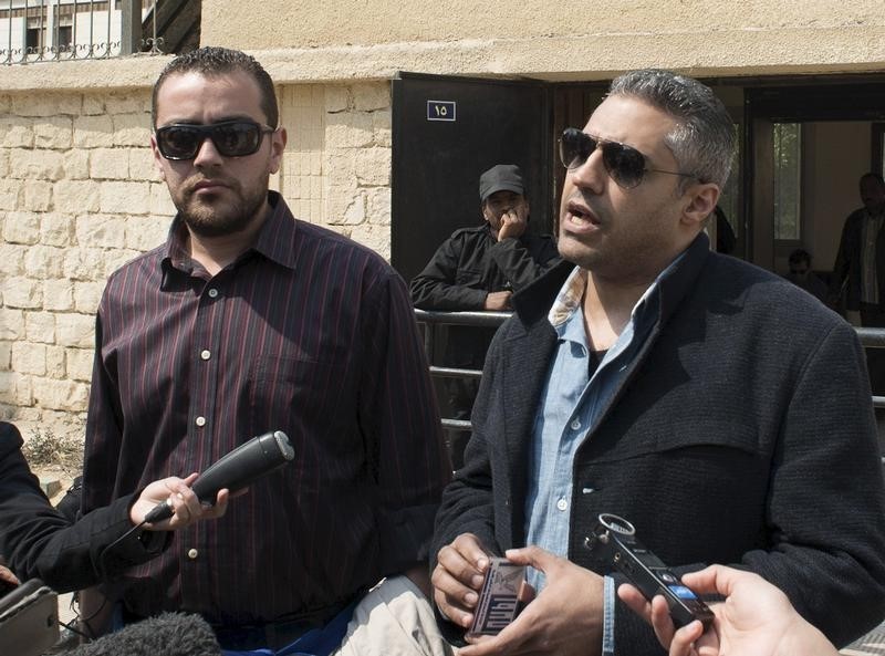 © Reuters. Al Jazeera television journalists Fahmy and Mohamed speak to the media outside of a court in Cairo