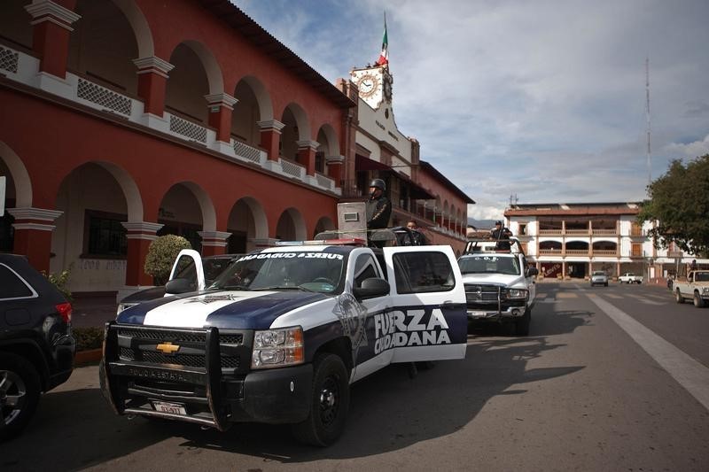 © Reuters. Police stand guard outside the town hall after a shooting between federal forces and armed civilians in the town of Apatzingan