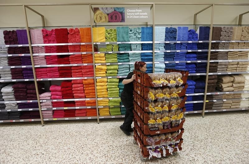 © Reuters. A bakery employee pushes a cart with loaves of bread past a towel display at a Tesco Extra supermarket in Watford, north of London