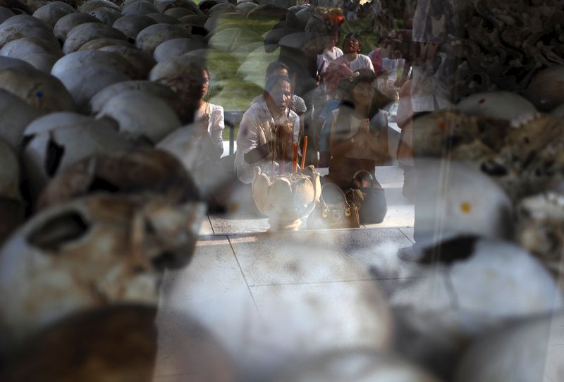 © Reuters. Women pray in front of the skulls and bones of victims of the Khmer Rouge regime during a Buddhist ceremony at Choeung Ek, a "Killing Fields" site located on the outskirts of Phnom Penh