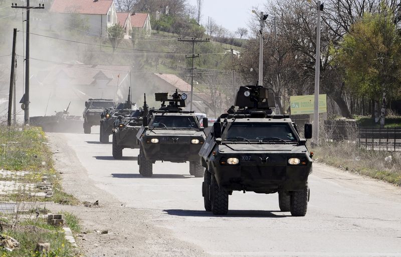 © Reuters. Police armed personnel carriers travel down a road to the village of Goshince from where police officers were taken hostage overnight, north of the capital Skopje 