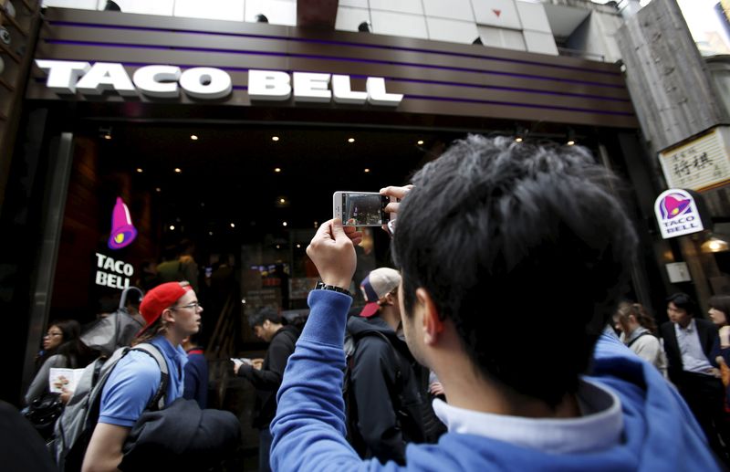 © Reuters. Man takes picture of first Taco Bell fast-food restaurant in Japan at Tokyo's Shibuya shopping district