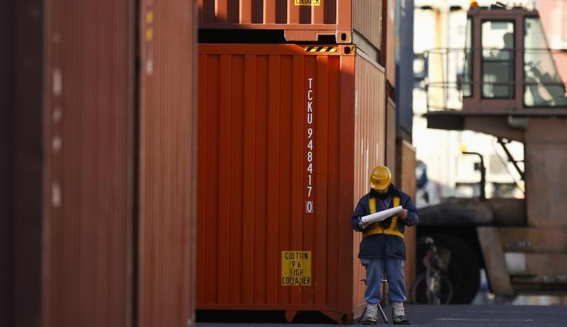 © Reuters. A worker reads documents at a container yard near a port in Tokyo