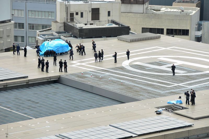 © Reuters. Police and security officers investigate an unidentified drone which was found on the rooftop of Prime Minister Shinzo Abe's official residence in Tokyo