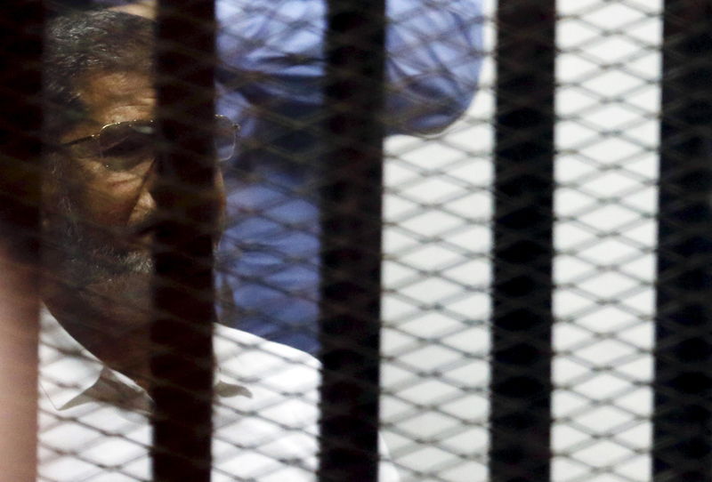 © Reuters. Ousted Egyptian President Mohamed Mursi looks on from behind bars, along with other Muslim Brotherhood members at a court in the outskirts of Cairo