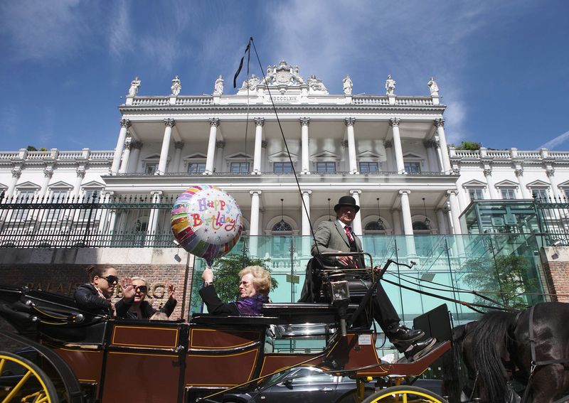 © Reuters. Passengers wave to journalists from a traditional Fiaker horse-carriage as they pass Palais Coburg hotel in Vienna