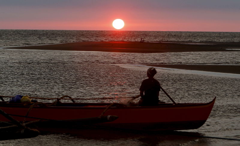 © Reuters. A fisherman watches sunset in the  South China Sea, about 130 nautical miles from Scarborough Shoal in the coastal town of Masinloc