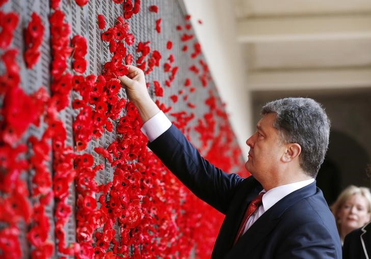 © Reuters. Ukraine's President Petro Poroshenko places a poppy in the World War I Honour Roll during their visit to the Australian War Memorial in Canberra