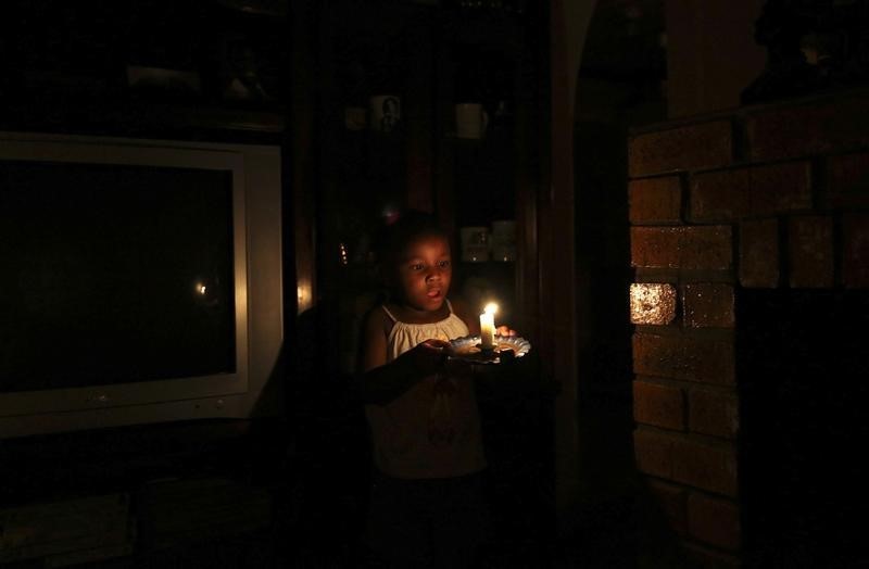 © Reuters. Four year old Mandisa holds a candle as she helps her grandmother during load shedding in Soweto