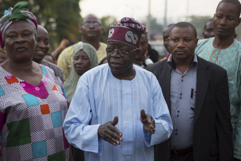 © Reuters. Former governor of Lagos state Bola Ahmed Tinubu speaks to electoral officials before voting in governorship elections in Lagos