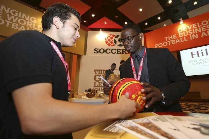 © Reuters. Louis Saha signs a ball during the Soccerex Asian Forum at the Dead Sea