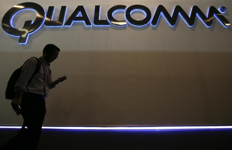 © Reuters. A man walks past Qualcomm stand while attending during the Mobile World Congress in Barcelona 