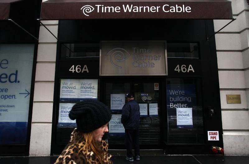 © Reuters. A woman walks past the old Time Warner Cable headquarters as a man tries to enter the building in New York