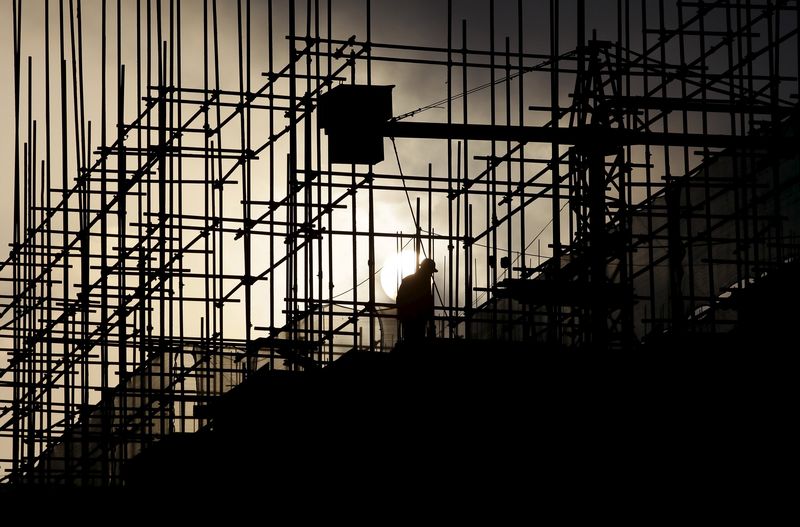 © Reuters. A labourer works during sunrise at a construction site of a residential complex in Puer