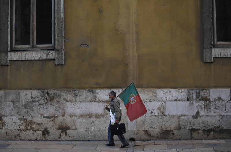 © Reuters. Man holds a Portuguese national flag as he shouts slogans against government policies in downtown Lisbon