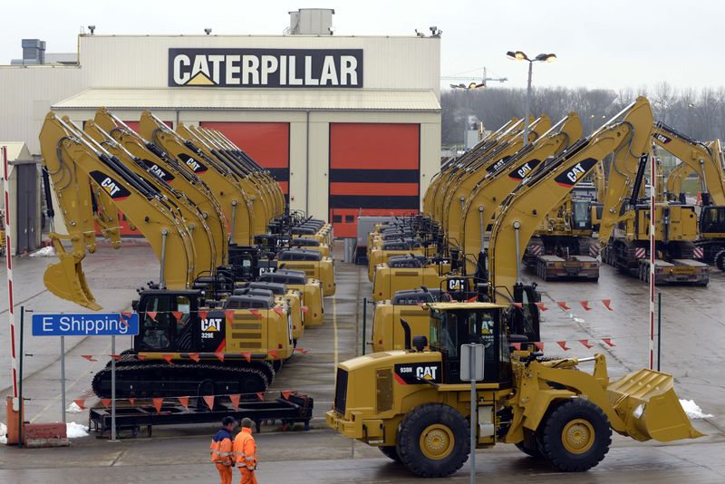 © Reuters. Workers walk past Caterpillar excavator machines at a factory in Gosselies