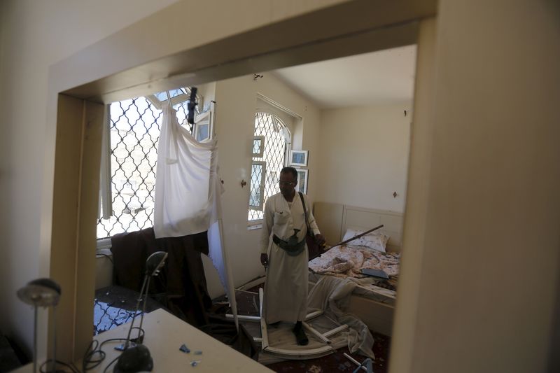 © Reuters. A guard is reflected in a bedroom mirror as he looks at damage caused by air strike by Saudi-led coalition that struck nearby missile base, in Yemen's capital Sanaa