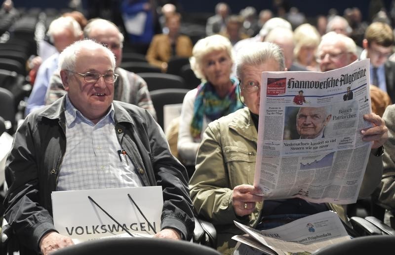 © Reuters. A shareholder reads a newspaper with a photo of Volkswagen's chairman of the supervisory board Ferdinand Piech as he attends the annual shareholders meeting of German carmaker in Hanover