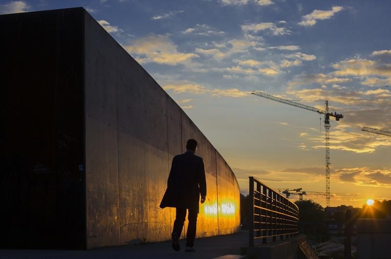 © Reuters. A man walks along the embankment of the river Spree during sunset in Berlin