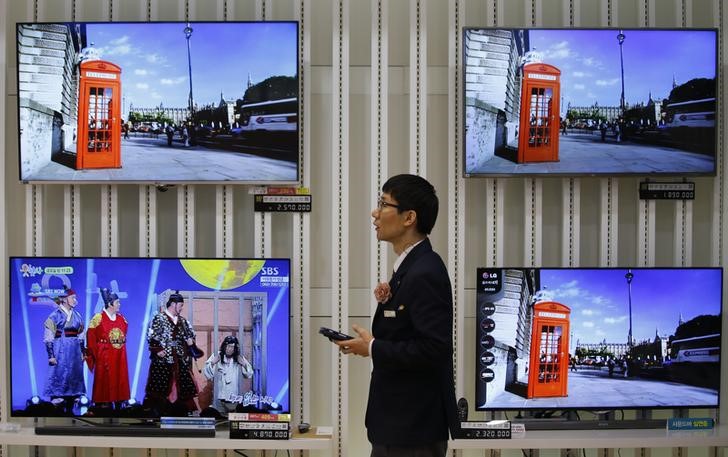 © Reuters. Um empregado usa seu celular em frente a televisores da LG em loja em Seul.