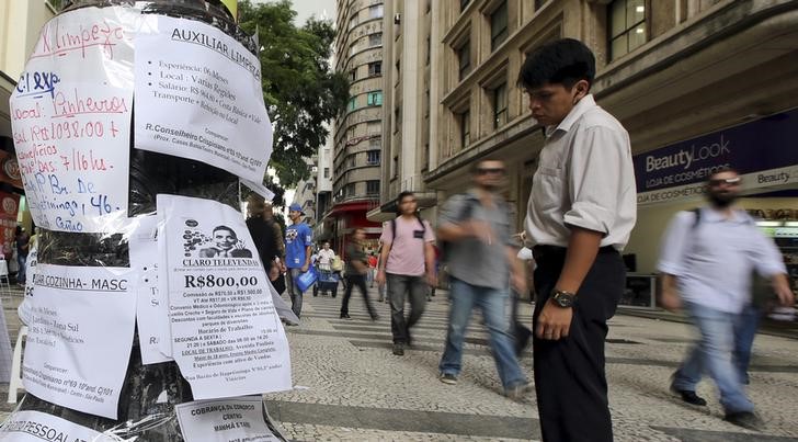 © Reuters. Homem observa anúncios de emprego dispostos em poste no centro de São Paulo 