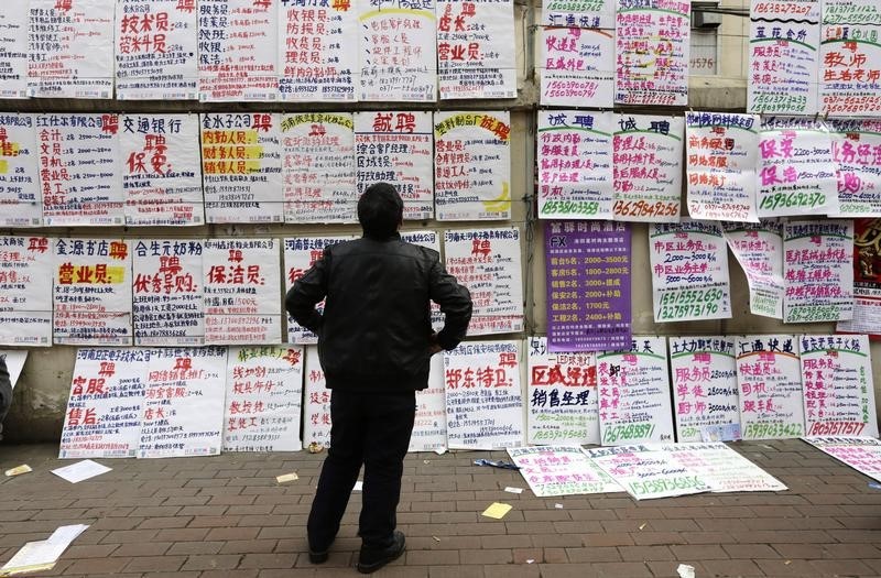 © Reuters. A man looks at job information at an employment fair beside a street in Zhengzhou