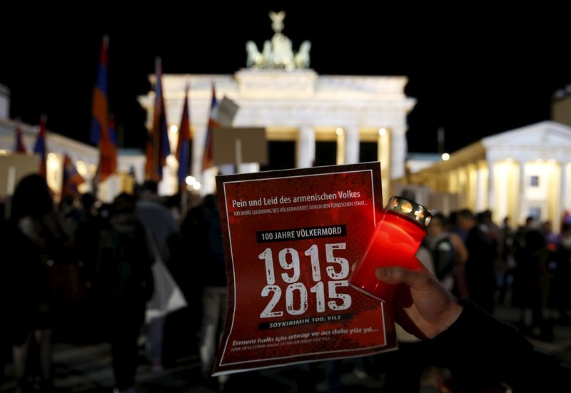 © Reuters. A participant holds a candle and a sign during a memorial march by armenians in front of the Brandenburg Gate in Berlin