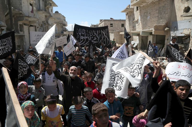 © Reuters. Residents hold up Nusra Front flags during a demonstration celebrating their take over of Idlib about a month ago and calling for the implementation of the Islamic Sharia law, in Al-Sakhour