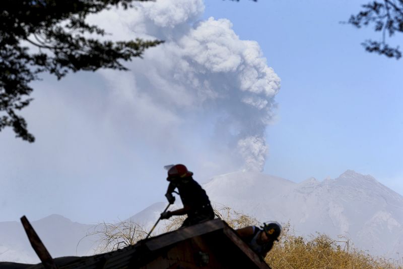 © Reuters. Bombeiros consertam telhado de sua base na cidade de Ensenada diante do vulcão Calbuco