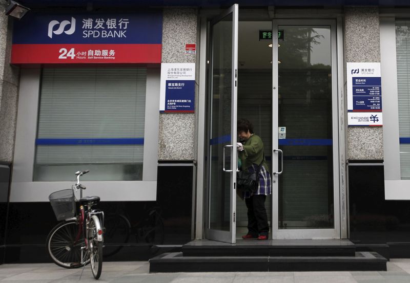 © Reuters. File photo of a woman leaving a branch of Shanghai Pudong Development Bank in Beijing