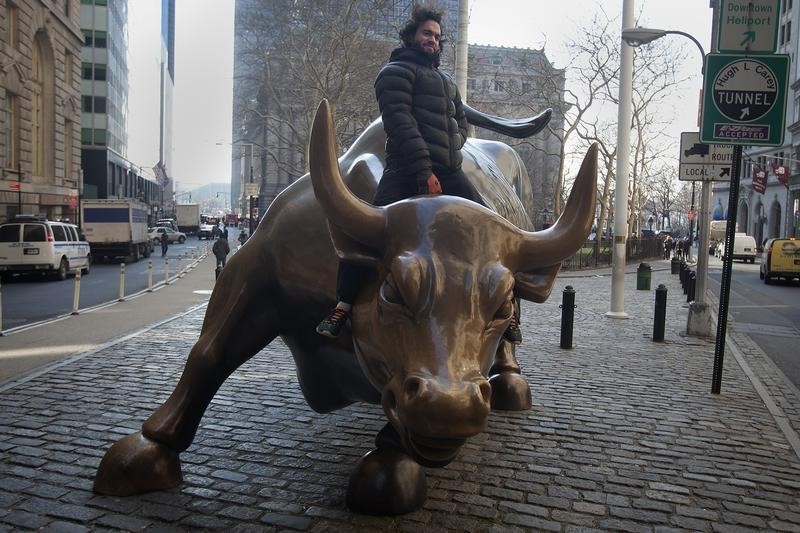 © Reuters. A tourist mounts the "Charging Bull" statue as he poses for a photo near Wall Street, in the Manhattan borough of New York