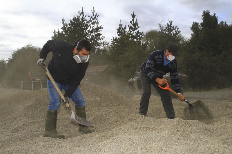 © Reuters. Homens usam pás para retirar de estrada cinzas expelidas por vulcão Calbuco, no Chile