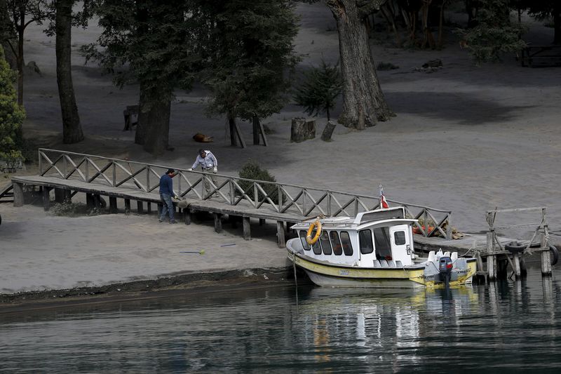 © Reuters. Residents clean a dock at Petrohue lake which was hit by ashes from Calbuco volcano, in the vicinity of Puerto Montt city 